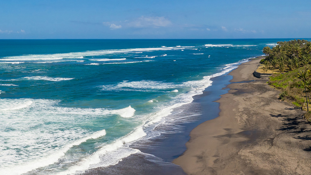 Pemandangan Pantai Seseh dengan pasir hitam, ombak laut, dan suasana pantai yang tenang.
